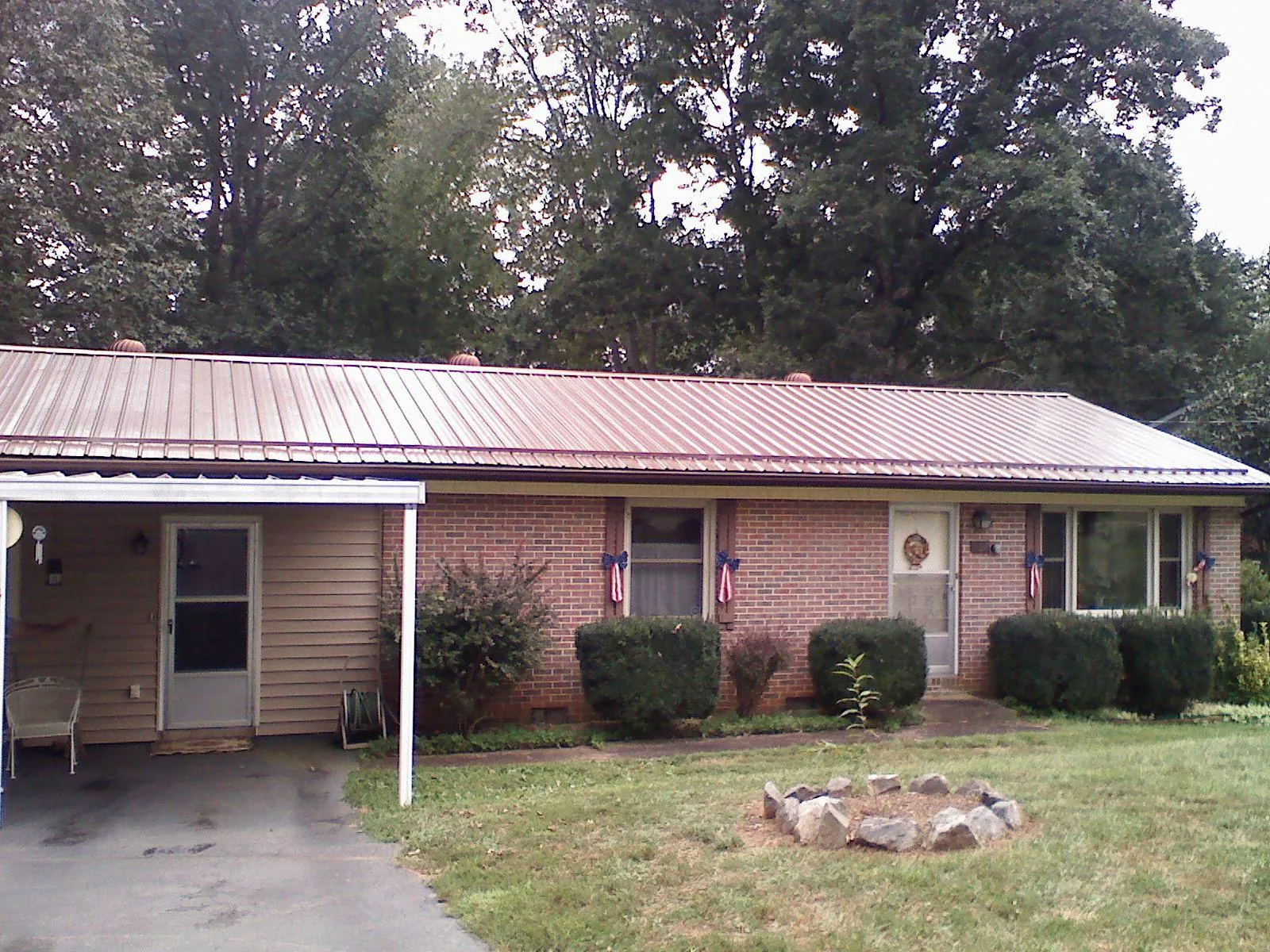 Bronze metal roof and carport on a brick ranch home — Roof Repair work by our crew in Blissfield